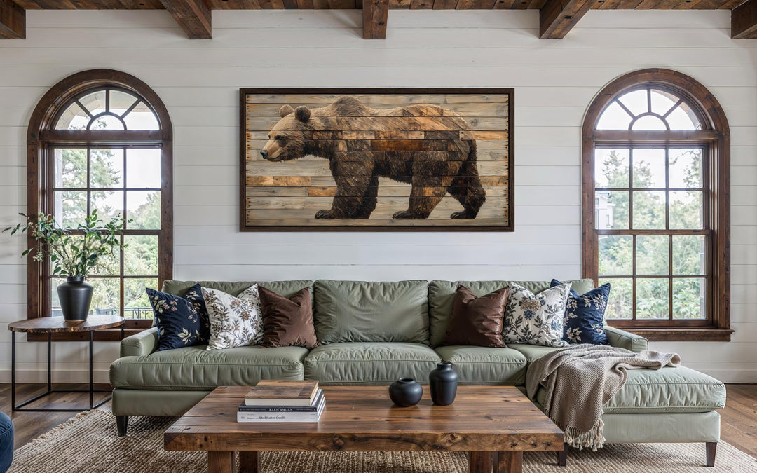 Rustic brown bear wall art on a wood-style canvas hangs above a green sofa in a cabin-style room.