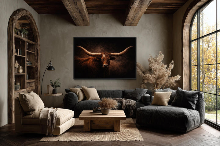 Brown longhorn bull canvas print with wide horns above a sofa in a rustic western living room.