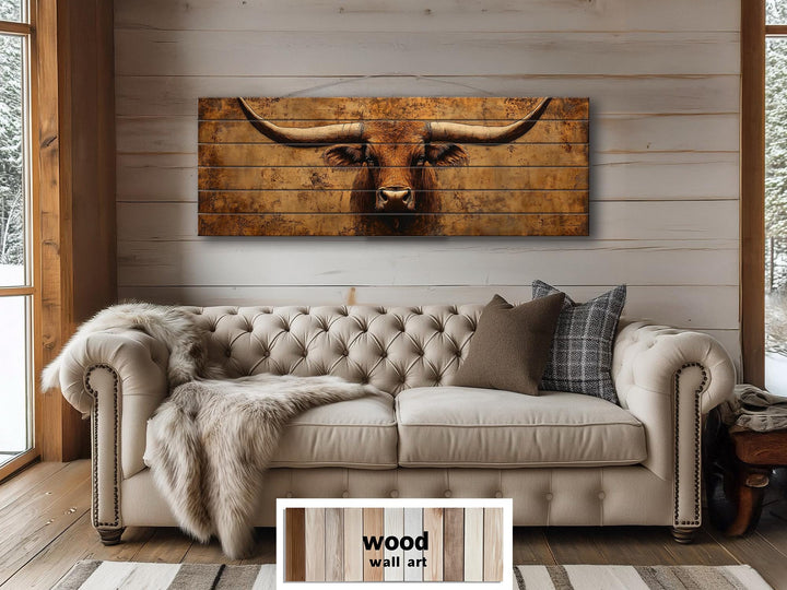 Long narrow wood wall art featuring a brown longhorn steer above a beige tufted sofa.