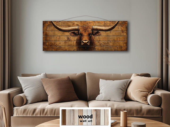 Brown longhorn steer printed on long, narrow distressed wood planks hanging above a tan sofa.