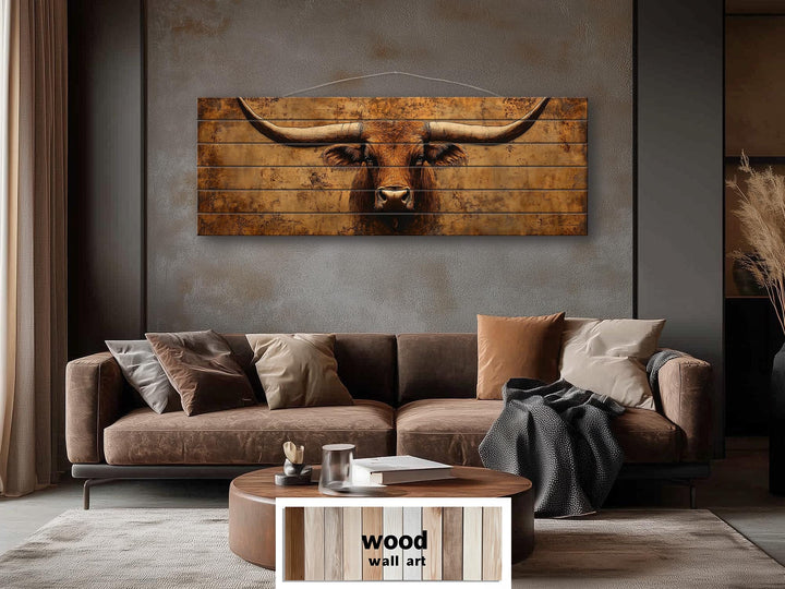 Brown longhorn steer printed on horizontal distressed wood planks above a brown sofa.
