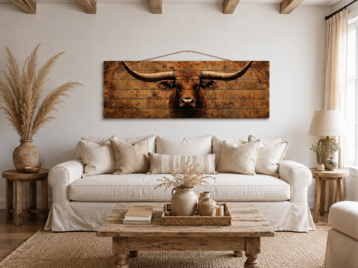Brown Longhorn Long Narrow Distressed Wood Wall Art hanging above a white sofa in a rustic room.
