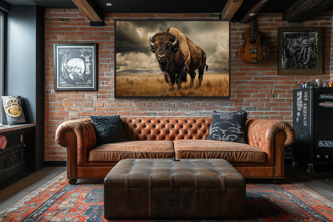 Buffalo in the wild framed canvas wall art hanging above a leather sofa in a rustic brick room.