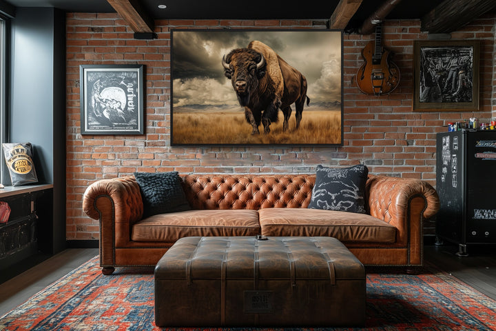Buffalo in the wild framed canvas wall art hanging above a leather sofa in a rustic brick room.