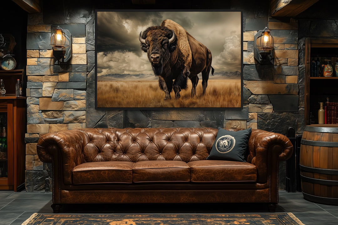 Buffalo in the wild framed canvas wall art hanging above a brown leather sofa in a rustic room.