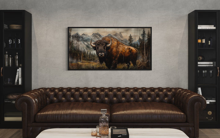 Rustic wood framed canvas of a buffalo in Yellowstone, hung above a brown leather sofa.