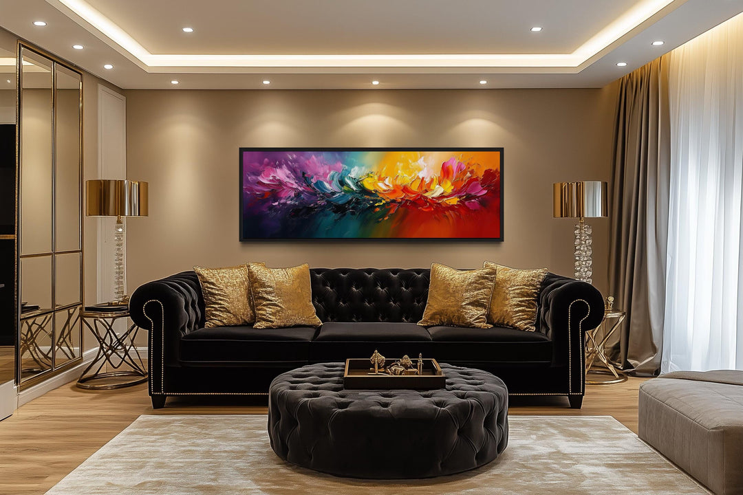 Burst of Color long horizontal rainbow abstract canvas wall art above a black sofa in a living room.