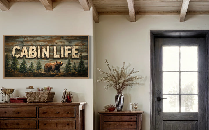 Cabin Life framed canvas wall art featuring a bear and fir trees above a rustic wooden dresser.