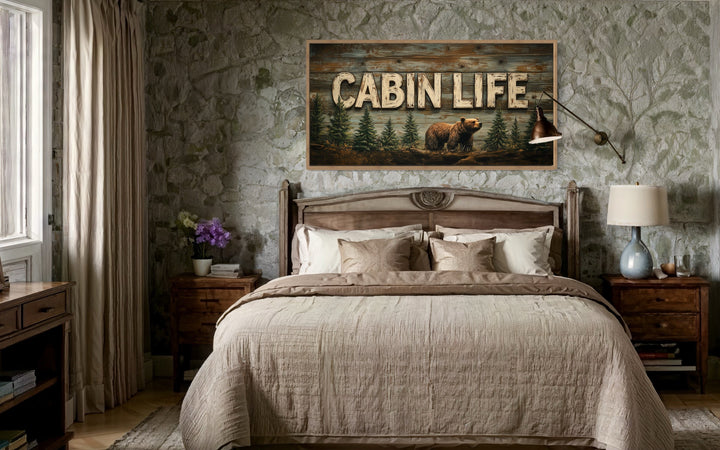 Cabin Life Sign With Bear And Fir Trees Framed Canvas Wall Art hanging above a bed in a rustic room.