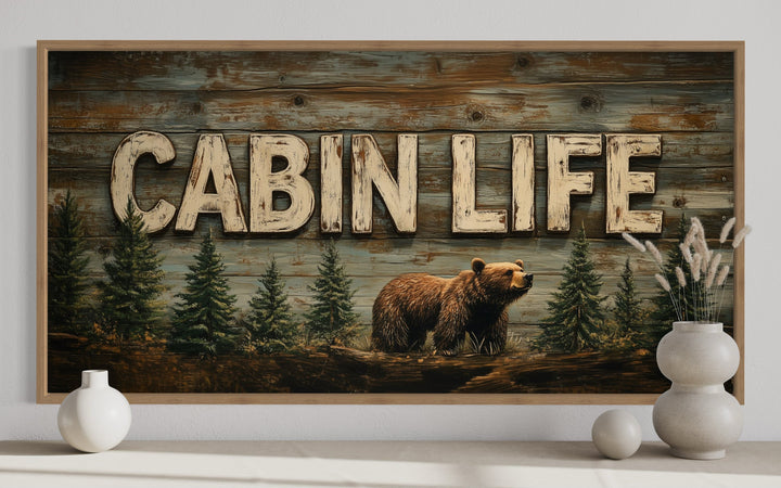 Cabin Life framed canvas wall art featuring a bear and fir trees on a rustic wood-look background.