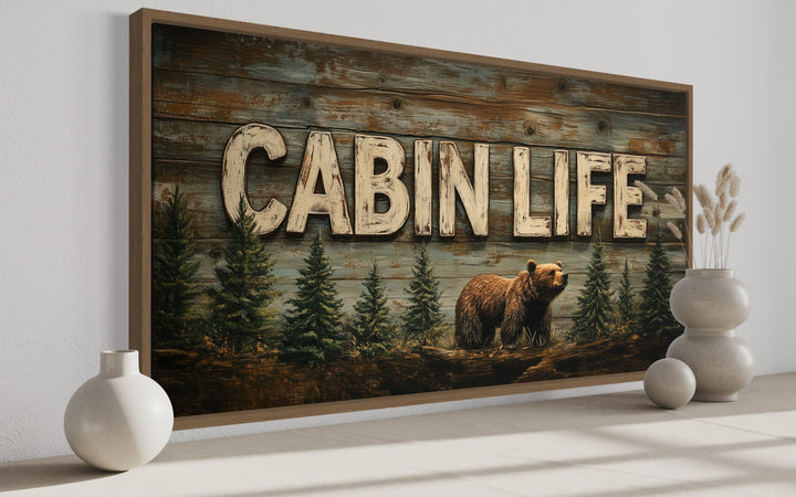 Cabin Life framed canvas wall art featuring a bear and fir trees on a rustic wood-textured background