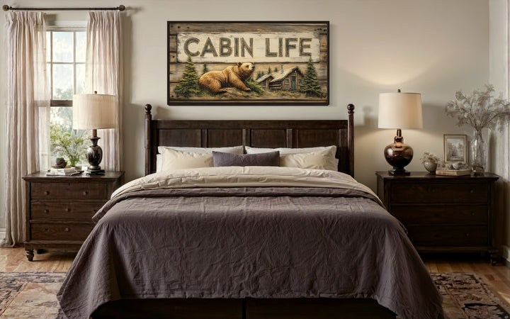 Cabin Life Sign framed canvas wall art with a bear and log house above a dark wood bed.