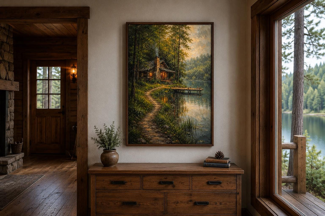 Vertical canvas print of a rustic cabin by a lake in a sunlit forest, hung above a wooden dresser.