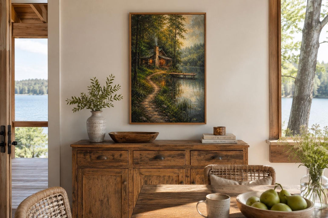 Vertical canvas print of a cozy forest cabin by a lake, hanging above a rustic wooden sideboard.