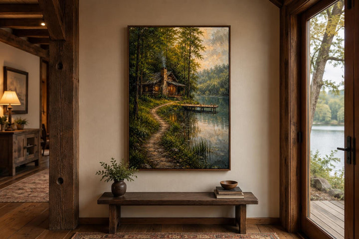 Vertical canvas print of a rustic cabin by a lake, displayed in a warm, wood-accented entryway.