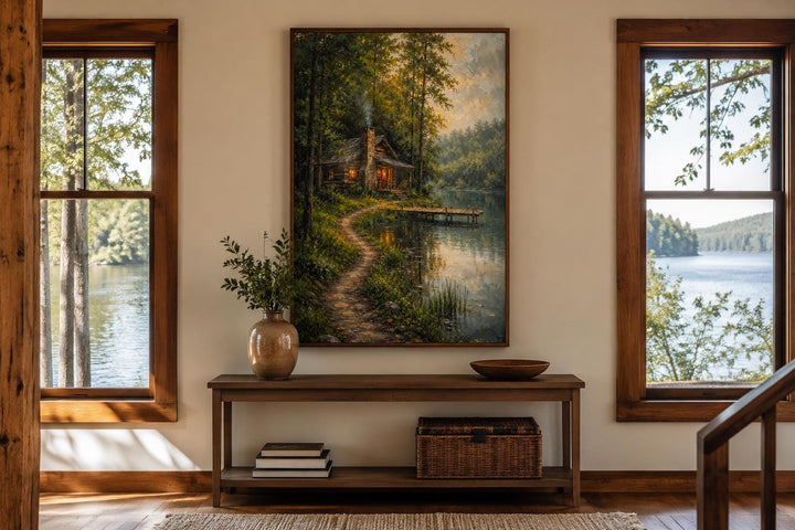 Vertical canvas print of a rustic forest cabin by a lake, displayed above a wooden console table.