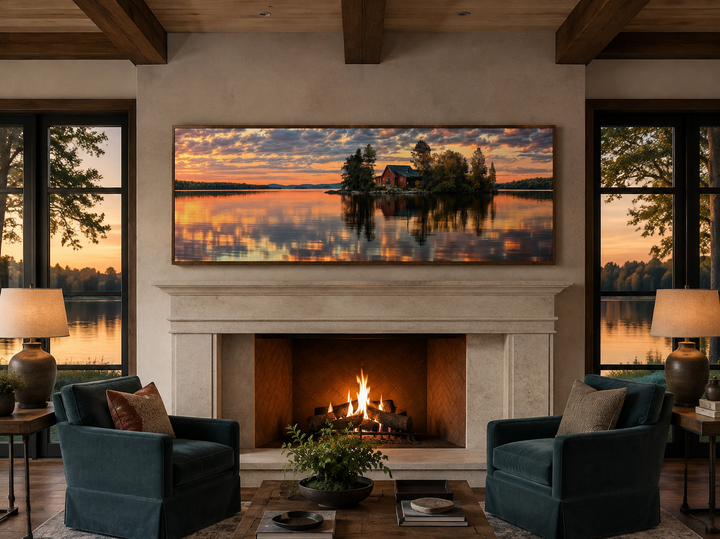 Long horizontal framed canvas wall art of a cabin on a lake at sunset above a fireplace.