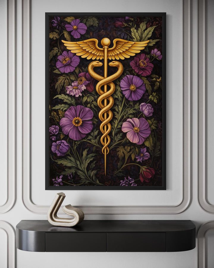 A framed canvas print of a golden caduceus symbol surrounded by purple flowers on a dark background.