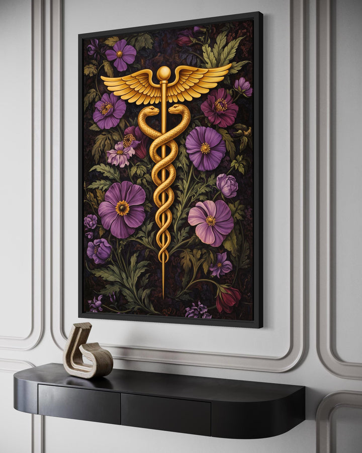 A framed canvas print of a golden caduceus symbol surrounded by vibrant purple and pink flowers.