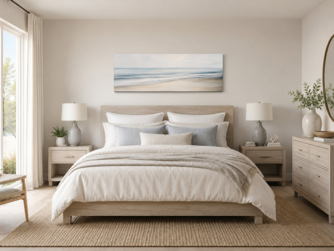 Calm long horizontal ocean framed canvas wall art above a bed in a coastal-style bedroom.