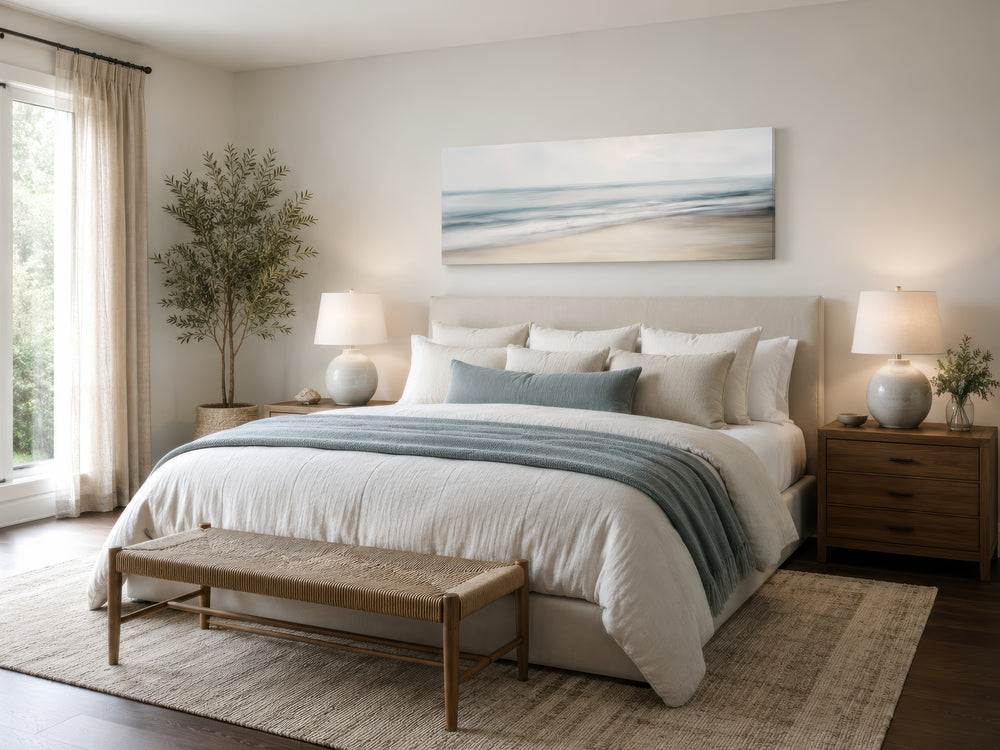 Calm long horizontal ocean framed canvas wall art above a bed in a serene coastal bedroom.