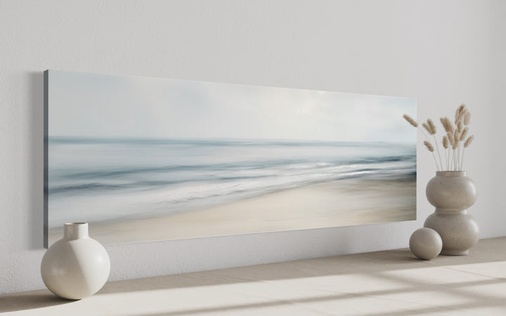 Calm long horizontal ocean framed canvas wall art with soft blue and gray coastal scene.