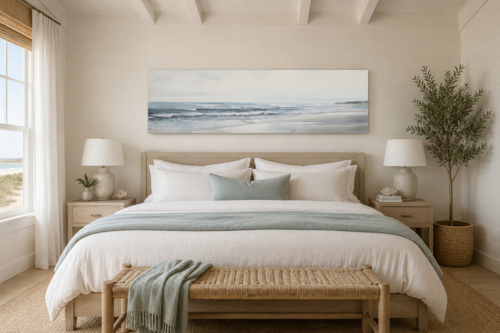 Long horizontal coastal framed canvas wall art featuring a minimalist beach landscape over a bed.