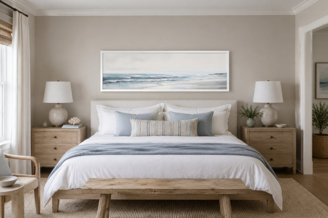 Long horizontal framed canvas wall art featuring a minimalist coastal beach scene above a bed.