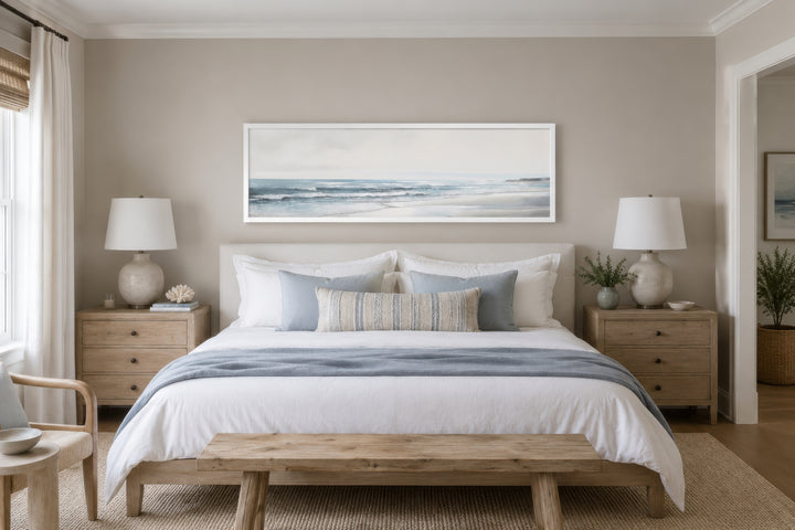 Long horizontal framed canvas wall art featuring a minimalist coastal beach scene above a bed.
