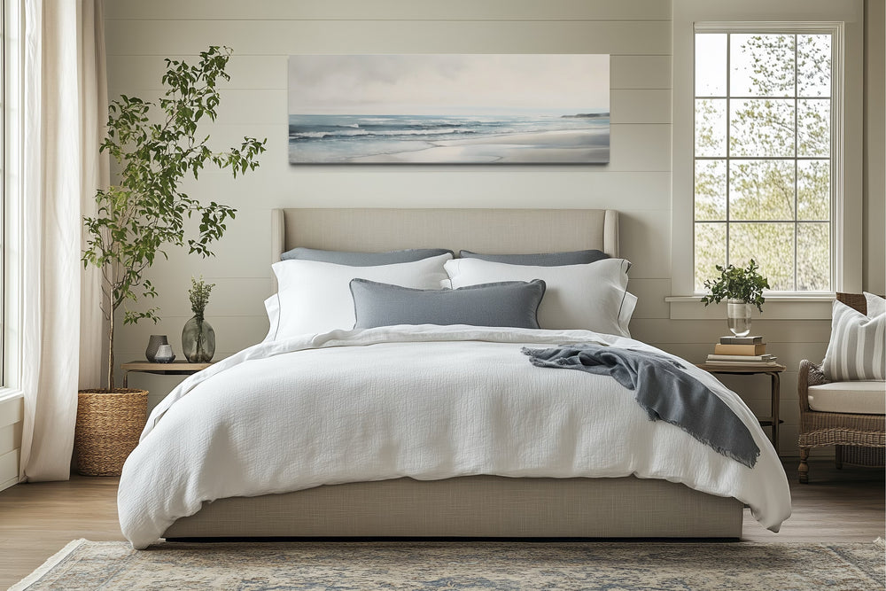 Long horizontal framed canvas wall art featuring a minimalist coastal beach scene above a bed.