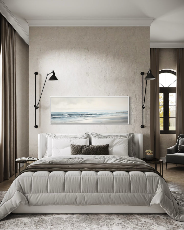 Long horizontal framed canvas wall art featuring a minimalist coastal beach scene above a bed.