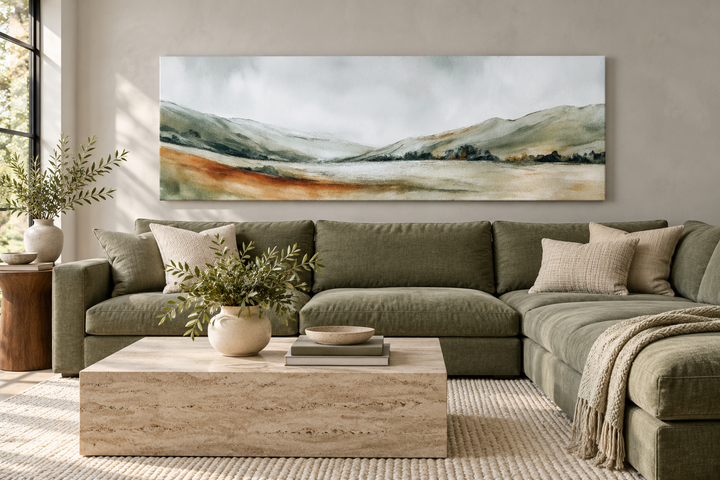 Wide panoramic canvas print of a minimalist green landscape above a sage green sectional sofa.