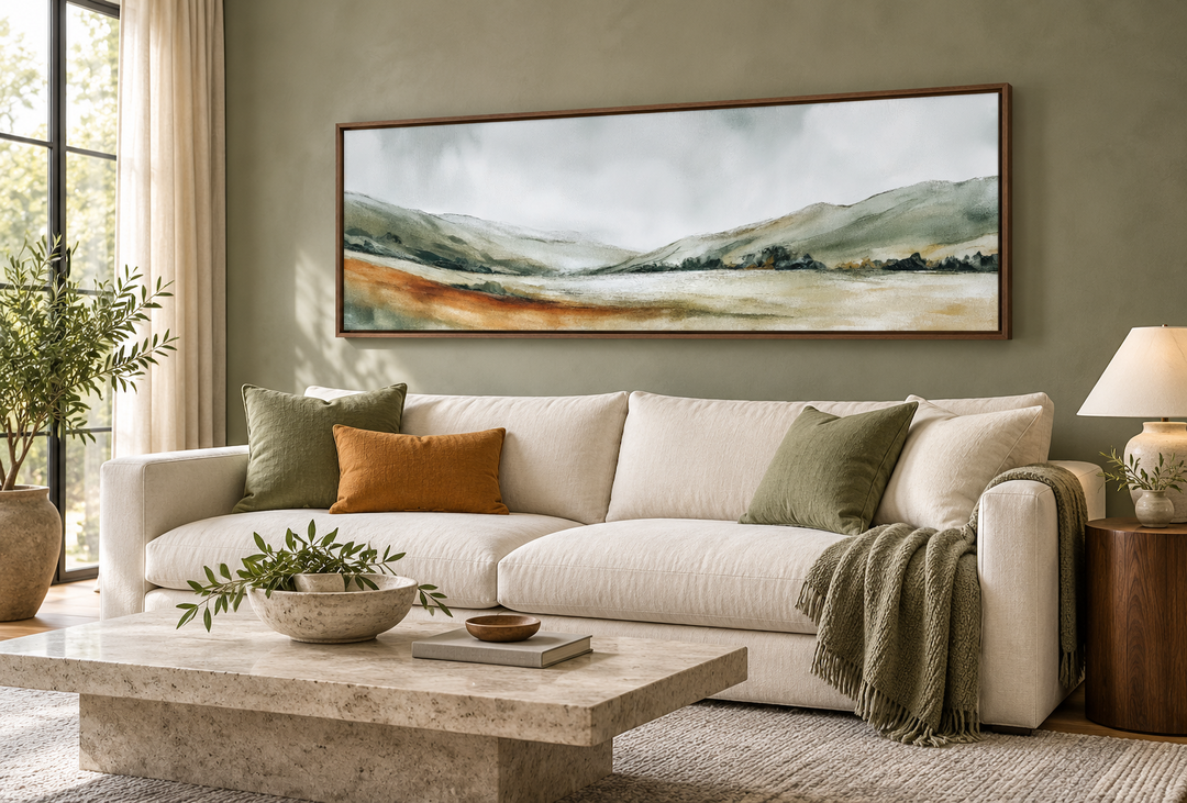 Panoramic green landscape wall art in a walnut frame above a white sofa in a sage green room.