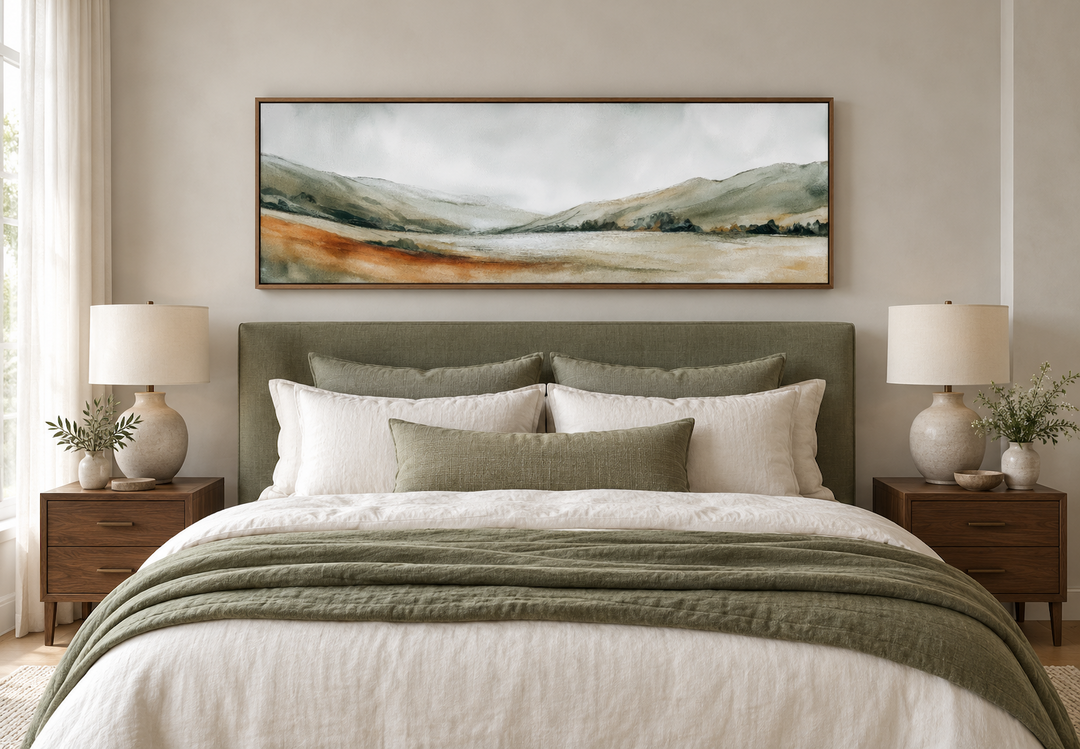 Panoramic green landscape canvas print in a walnut frame above a bed with sage and white bedding.
