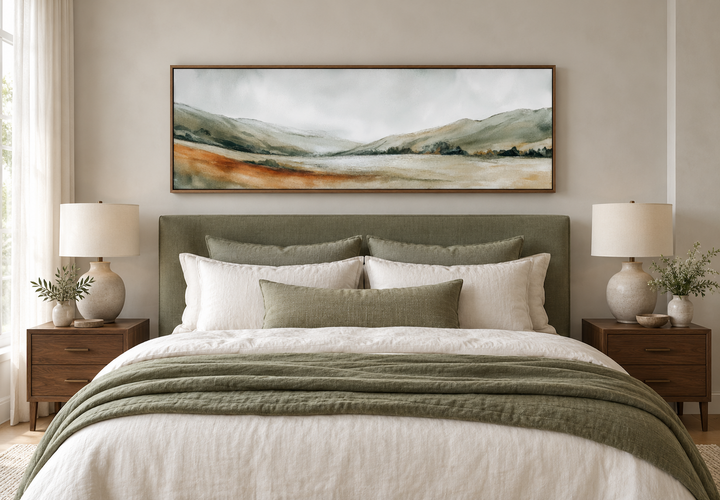 Panoramic green landscape canvas print in a walnut frame above a bed with sage and white bedding.