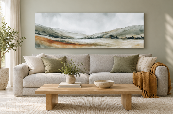Panoramic green landscape canvas print above a neutral sofa in a minimalist living room.