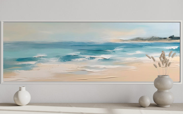 Panoramic framed canvas wall art of a calm ocean beach with neutral beige and aqua tones.