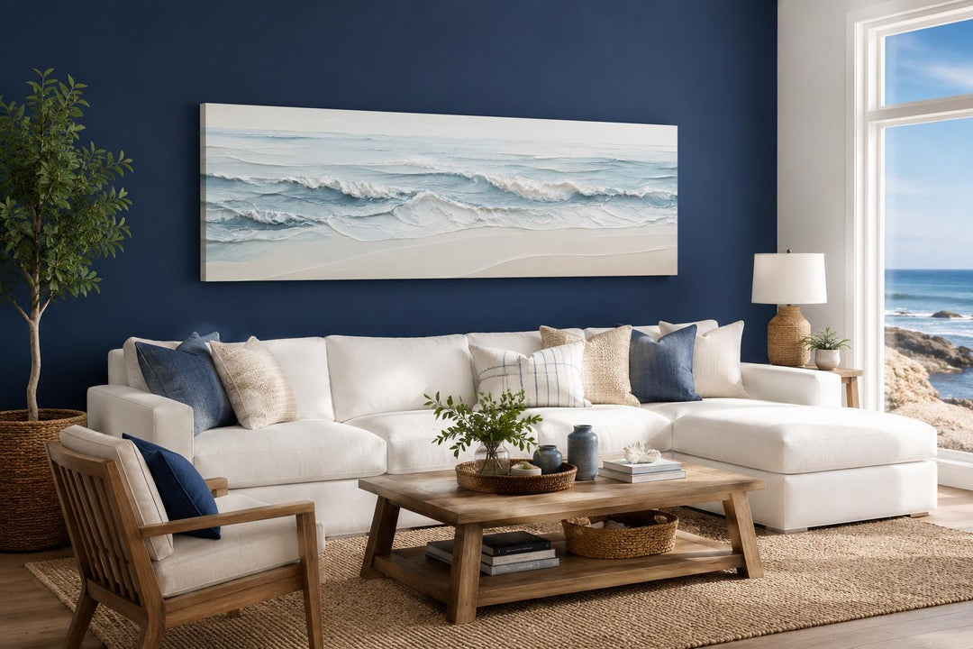 Wide horizontal canvas print of calm ocean waves in blue and cream tones above a white sofa.