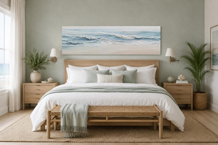 Wide horizontal canvas print of calm ocean waves in blue and cream above a wooden bed.