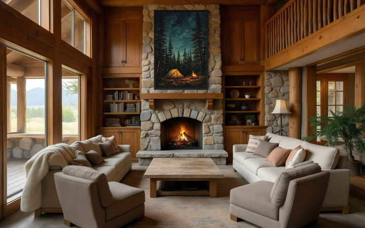 Campfire and tent in a pine forest canvas wall art hanging above a stone fireplace in a rustic cabin.