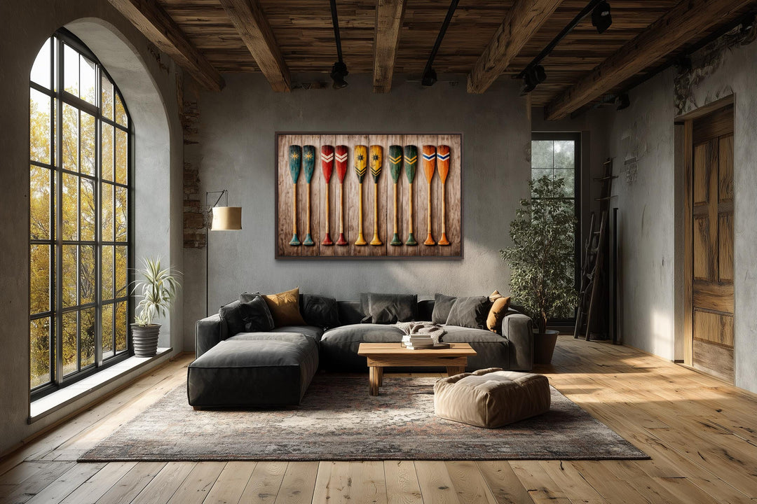 A horizontal canvas print of colorful, rustic canoe paddles hangs in a modern industrial living room.