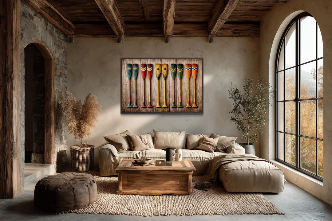A rustic canvas print of colorful wooden canoe paddles hangs in a cozy, earth-toned living room.