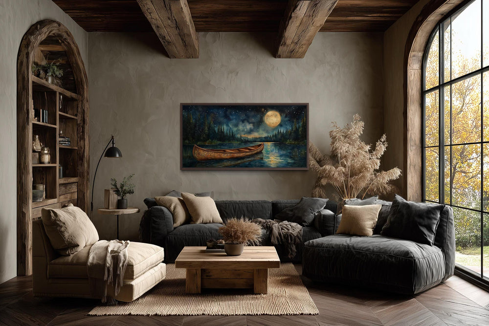 Canoe on moonlit lake and forest night scene canvas wall art hanging in a rustic living room.