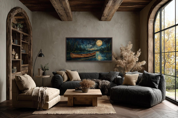 Canoe on moonlit lake and forest night scene canvas wall art hanging in a rustic living room.