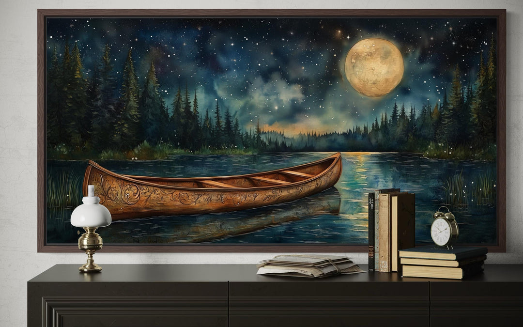 Canoe on moonlit lake and forest night scene canvas wall art displayed above a dark wood dresser.