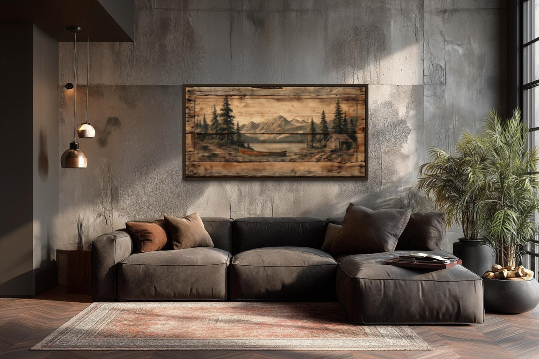 Canoe on mountain lake canvas wall art on a concrete wall above a dark grey sectional sofa.