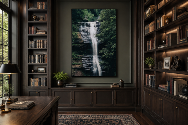 Vertical wall art of a cascading waterfall in a lush sage green forest above a dark wood cabinet.
