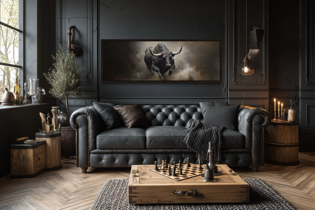 Charging bull long horizontal canvas print above a black leather sofa in a dark, masculine room.