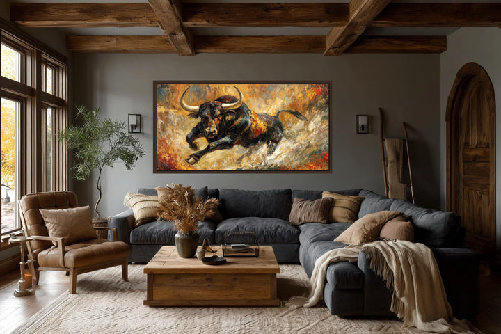 A large horizontal canvas print of a charging black bull hangs in a rustic, modern living room.
