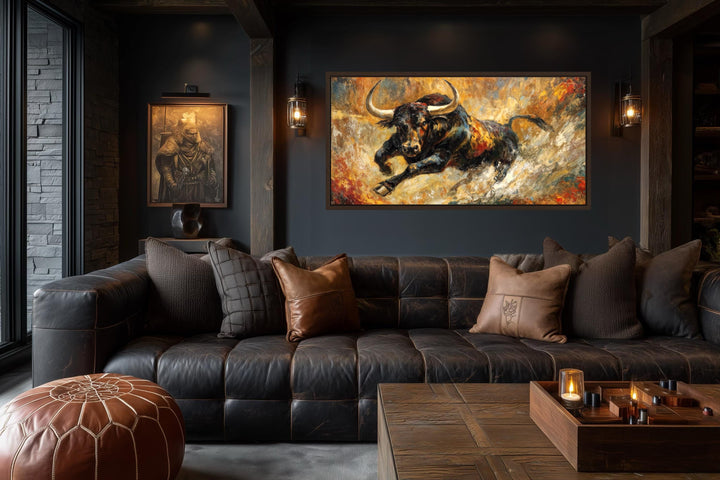 Charging bull canvas print with gold and red abstract background in a dark leather living room.